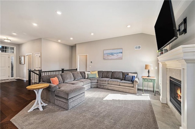 living room featuring visible vents, baseboards, recessed lighting, a fireplace, and vaulted ceiling