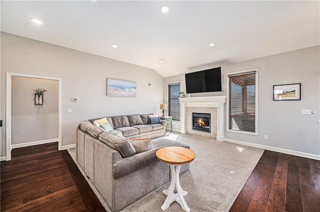 living room with baseboards, vaulted ceiling, recessed lighting, a tile fireplace, and hardwood / wood-style flooring