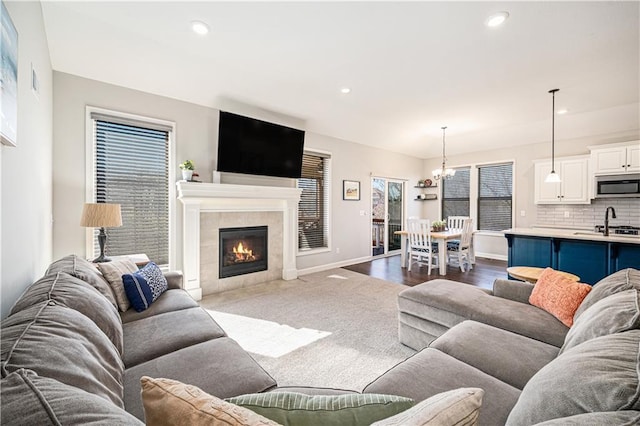 living area featuring recessed lighting, a tile fireplace, an inviting chandelier, and baseboards