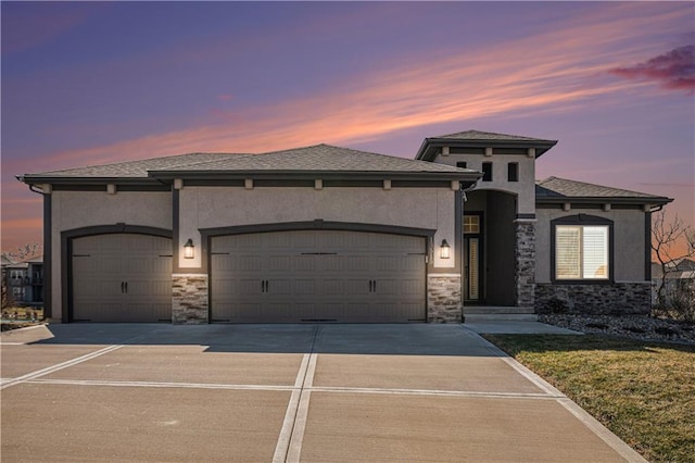 prairie-style house with an attached garage, stone siding, and stucco siding