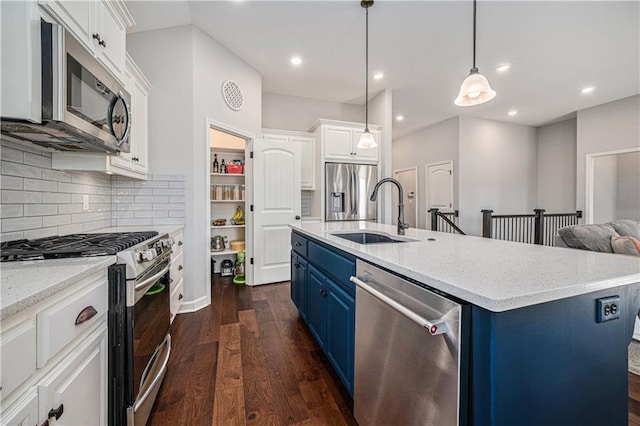 kitchen with a sink, backsplash, stainless steel appliances, blue cabinets, and dark wood-style flooring