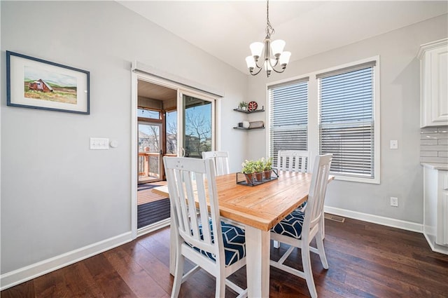 dining space featuring dark wood-style floors, a chandelier, and baseboards