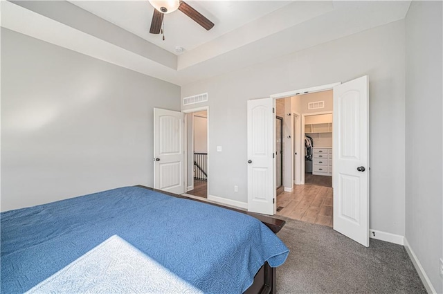 bedroom featuring carpet, a tray ceiling, baseboards, and visible vents