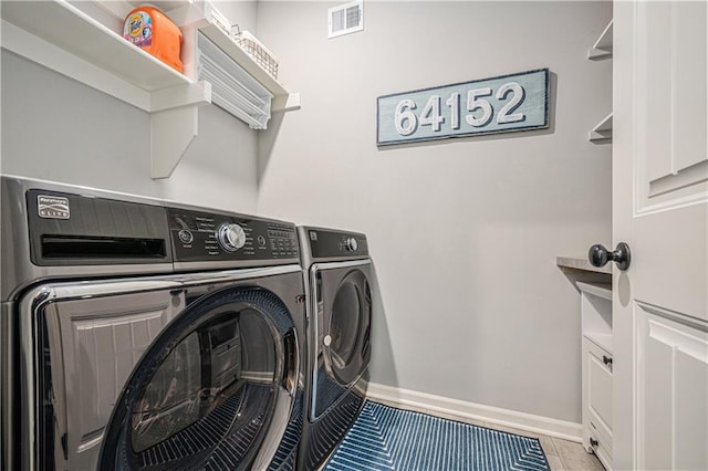 laundry area featuring tile patterned floors, visible vents, washing machine and dryer, baseboards, and laundry area