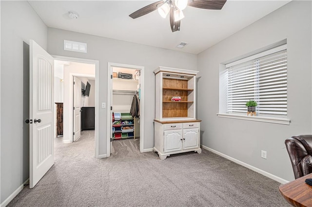 office featuring a ceiling fan, light colored carpet, visible vents, and baseboards