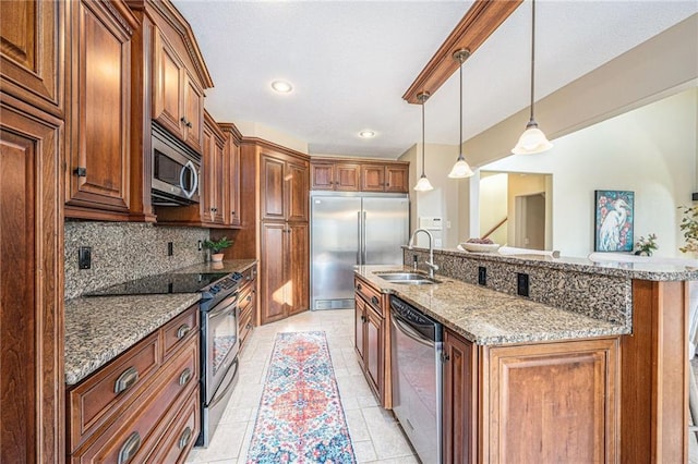 kitchen featuring sink, decorative light fixtures, appliances with stainless steel finishes, a kitchen island with sink, and backsplash