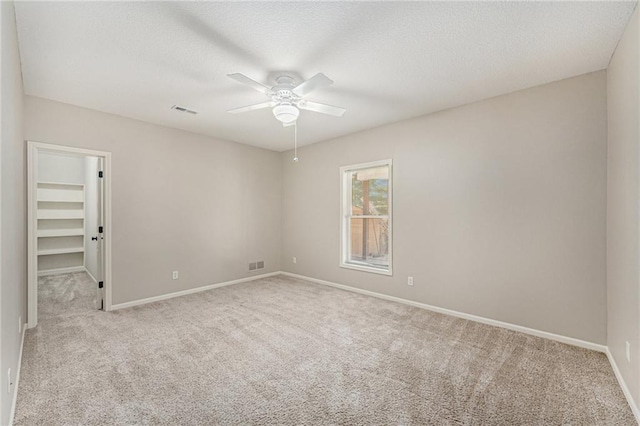 carpeted empty room with a textured ceiling and ceiling fan