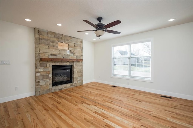 unfurnished living room featuring visible vents, a ceiling fan, wood finished floors, and a fireplace