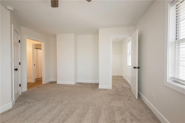 unfurnished bedroom with light colored carpet, baseboards, and ceiling fan