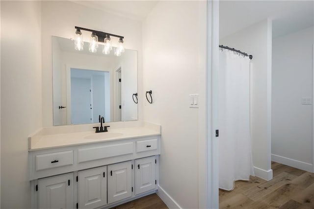 bathroom featuring a shower with shower curtain, baseboards, wood finished floors, and vanity