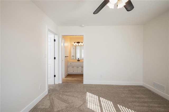 unfurnished bedroom featuring visible vents, ensuite bath, baseboards, and carpet floors