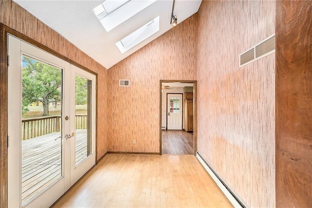 doorway to outside with a skylight, high vaulted ceiling, french doors, and light wood-type flooring