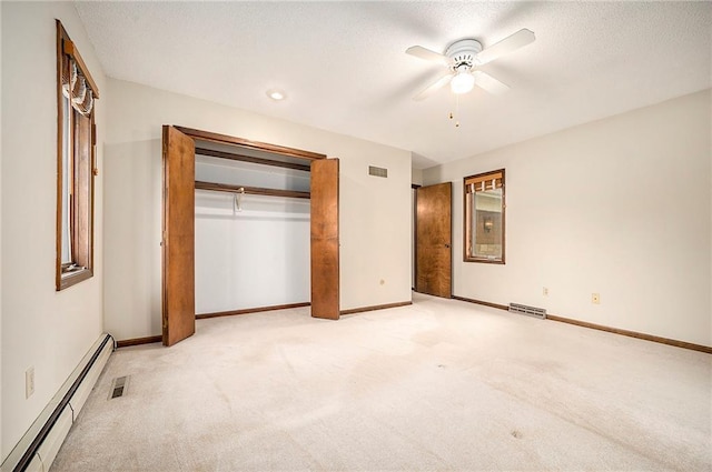 unfurnished bedroom with a baseboard radiator, light carpet, a textured ceiling, and a closet