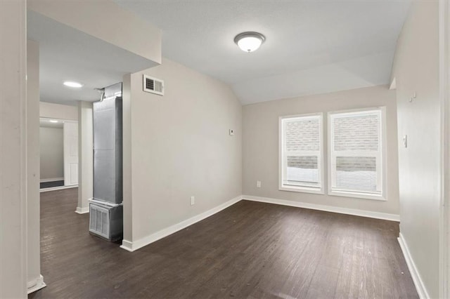 spare room featuring lofted ceiling and dark hardwood / wood-style floors