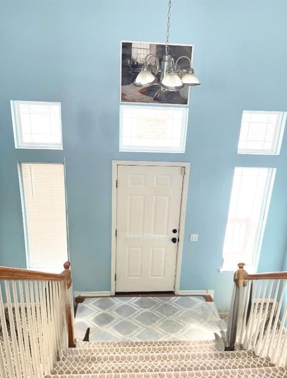 entryway with baseboards, a high ceiling, and a chandelier