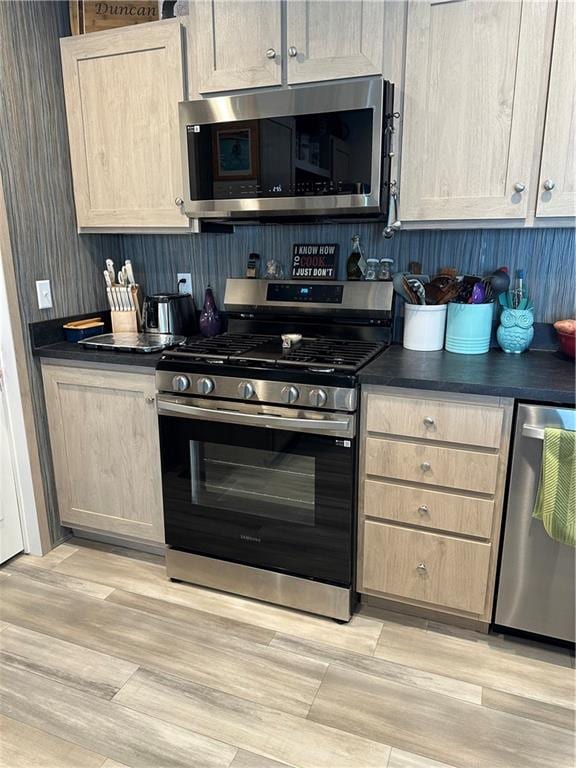 kitchen with dark countertops, light brown cabinets, and stainless steel appliances