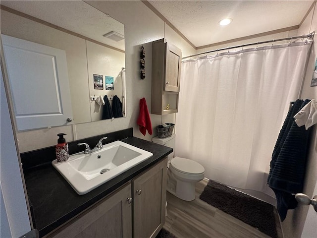 full bathroom featuring visible vents, toilet, vanity, wood finished floors, and a textured ceiling