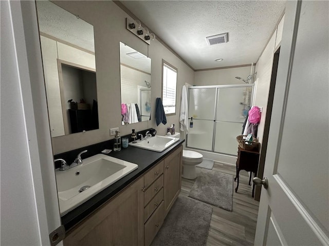 bathroom featuring wood finished floors, toilet, a textured ceiling, and a sink