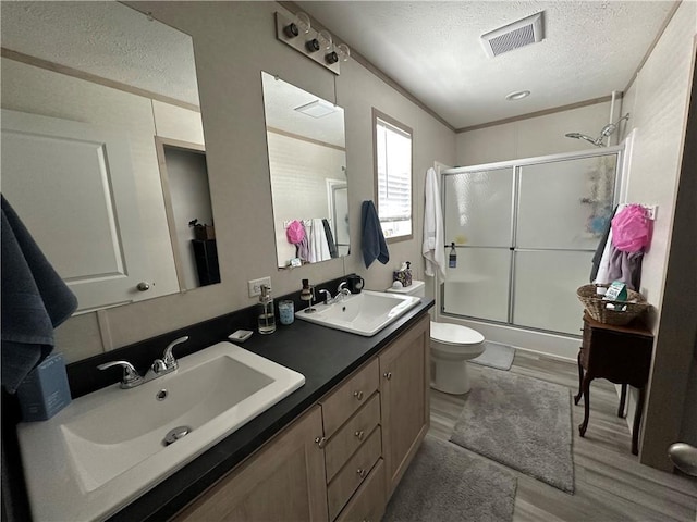 full bathroom featuring visible vents, toilet, a textured ceiling, and a sink