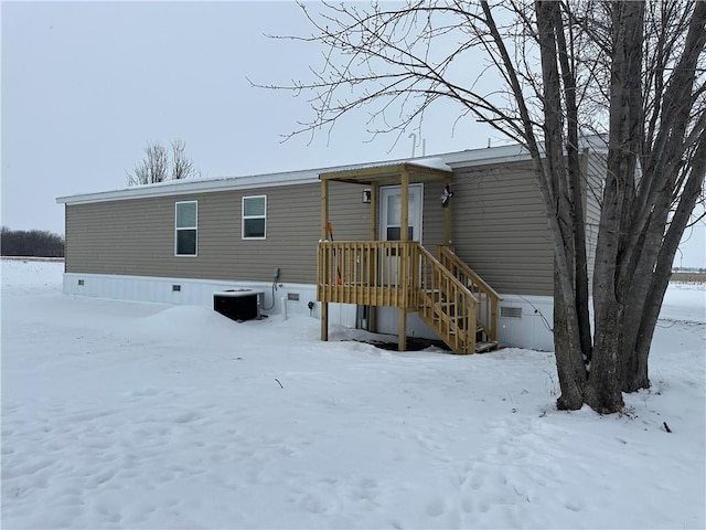 snow covered rear of property featuring crawl space and central AC unit