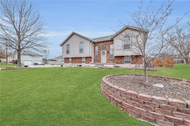 split foyer home featuring a garage, brick siding, and a front lawn