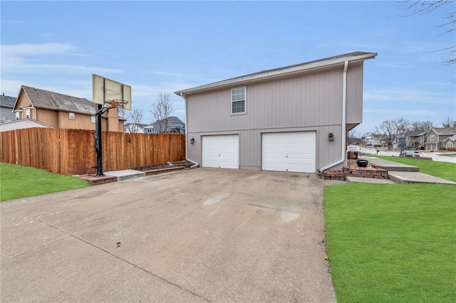 view of side of home featuring a garage, a residential view, fence, and a lawn