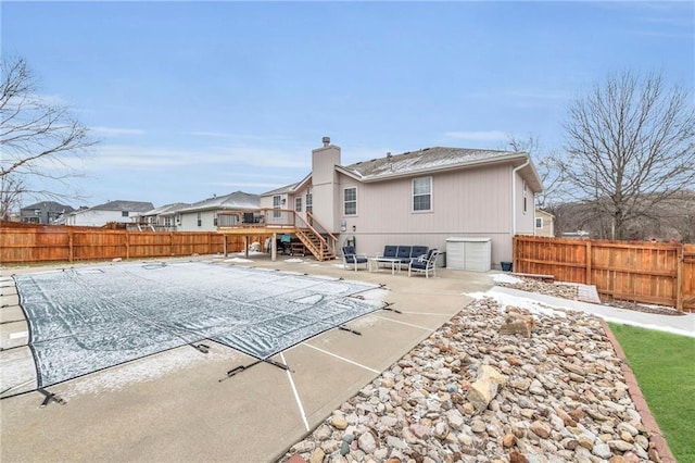 back of house featuring a garage, a fenced backyard, stairway, and a patio