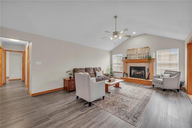 living area featuring lofted ceiling, ceiling fan, a fireplace, wood finished floors, and baseboards