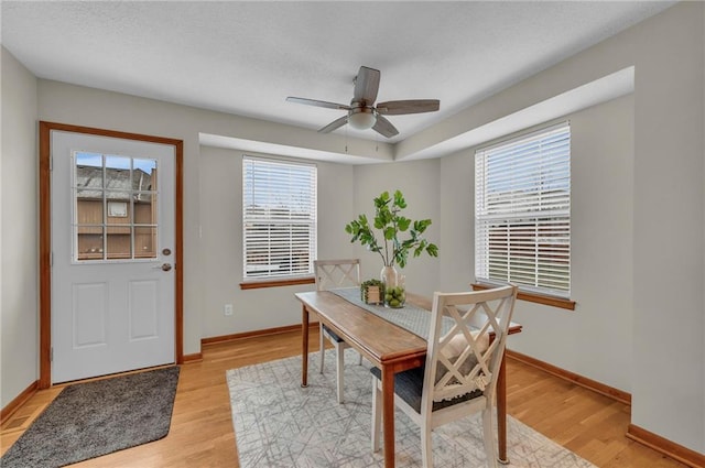 dining space with light wood finished floors, baseboards, and a ceiling fan