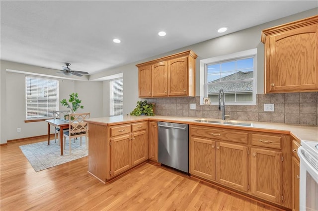 kitchen with dishwasher, light countertops, a peninsula, and a sink