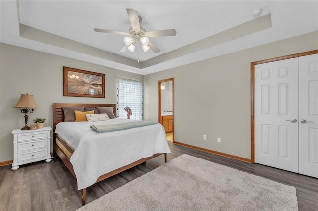 bedroom with baseboards, a raised ceiling, and dark wood finished floors