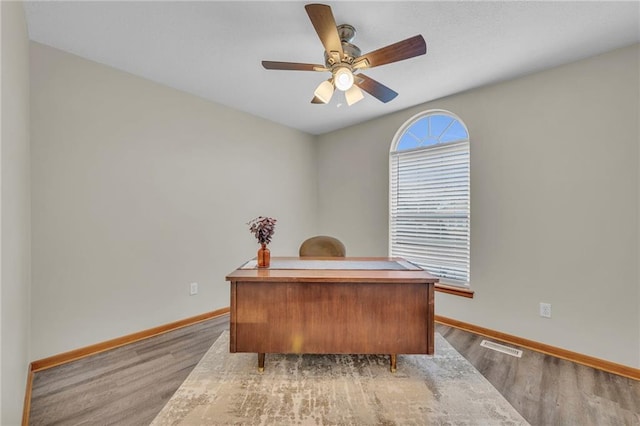 office space with light wood-type flooring, visible vents, ceiling fan, and baseboards