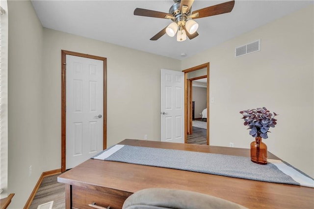 office area featuring baseboards, ceiling fan, visible vents, and wood finished floors