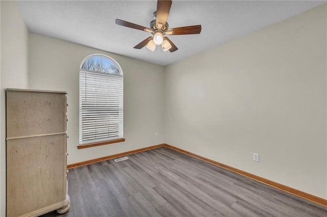 unfurnished room with a ceiling fan, baseboards, and wood finished floors