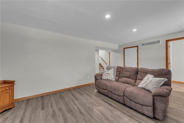 living area with light wood finished floors, recessed lighting, visible vents, baseboards, and stairs