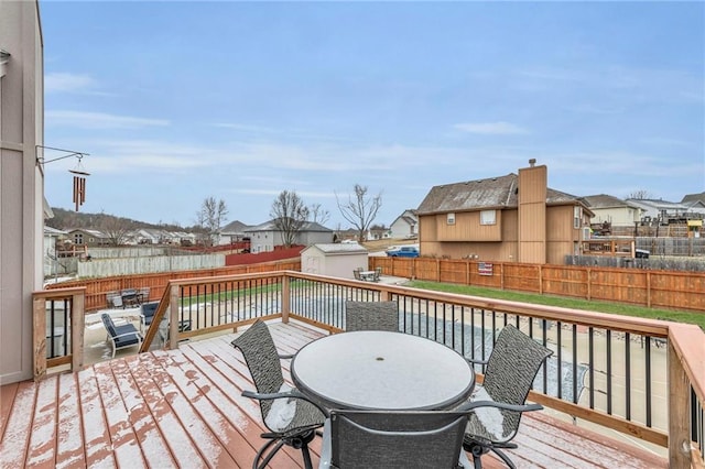 wooden deck with a storage shed, a fenced backyard, a residential view, an outdoor structure, and outdoor dining space