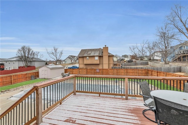 wooden terrace featuring a fenced backyard, a residential view, and a shed