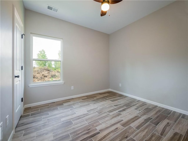 empty room featuring baseboards, a ceiling fan, visible vents, and wood tiled floor