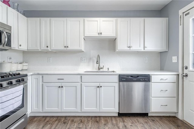 kitchen featuring stainless steel appliances, a sink, white cabinets, light countertops, and light wood-type flooring