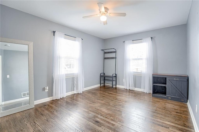 empty room featuring visible vents, ceiling fan, baseboards, and wood finished floors