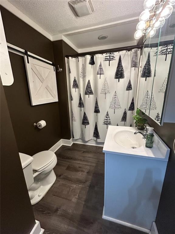 bathroom featuring hardwood / wood-style flooring, vanity, walk in shower, toilet, and a textured ceiling