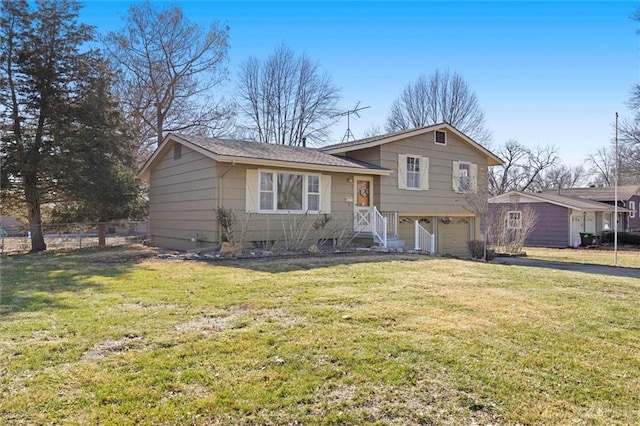 split level home featuring an attached garage, fence, and a front yard