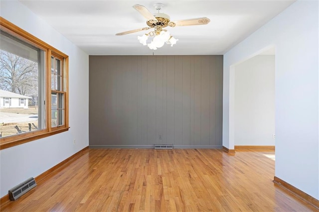 unfurnished room featuring baseboards, ceiling fan, visible vents, and light wood-style floors