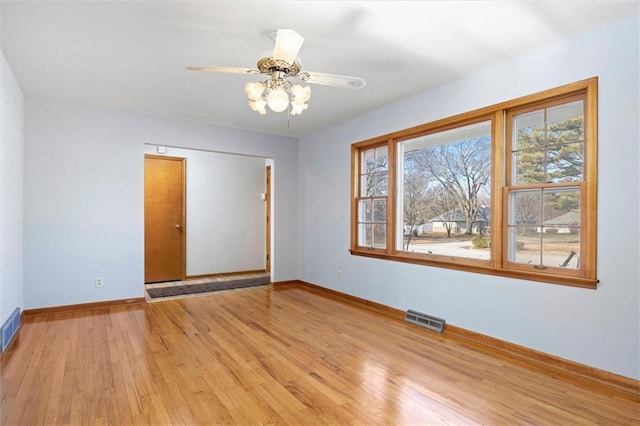 empty room with light wood-style floors, visible vents, ceiling fan, and baseboards