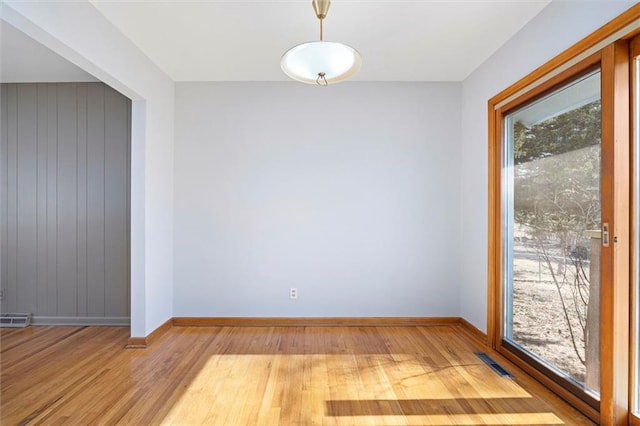 empty room featuring visible vents, baseboards, and wood finished floors