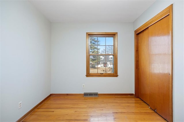 unfurnished bedroom featuring light wood-style floors, baseboards, visible vents, and a closet