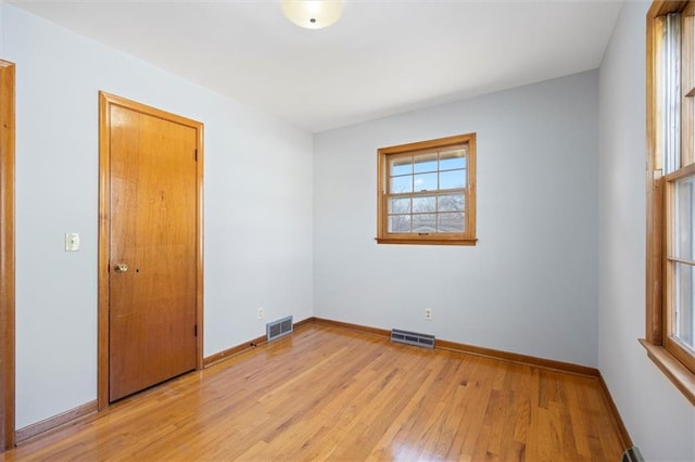 spare room featuring light wood-style flooring, visible vents, and baseboards