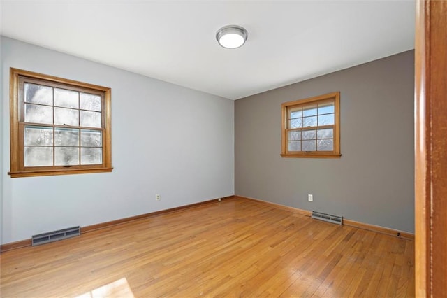 spare room with light wood-type flooring, baseboards, and visible vents