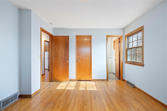 unfurnished bedroom featuring baseboards, visible vents, and light wood-style floors