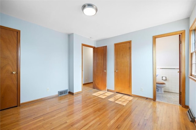 unfurnished bedroom with light wood-type flooring, ensuite bath, visible vents, and baseboards